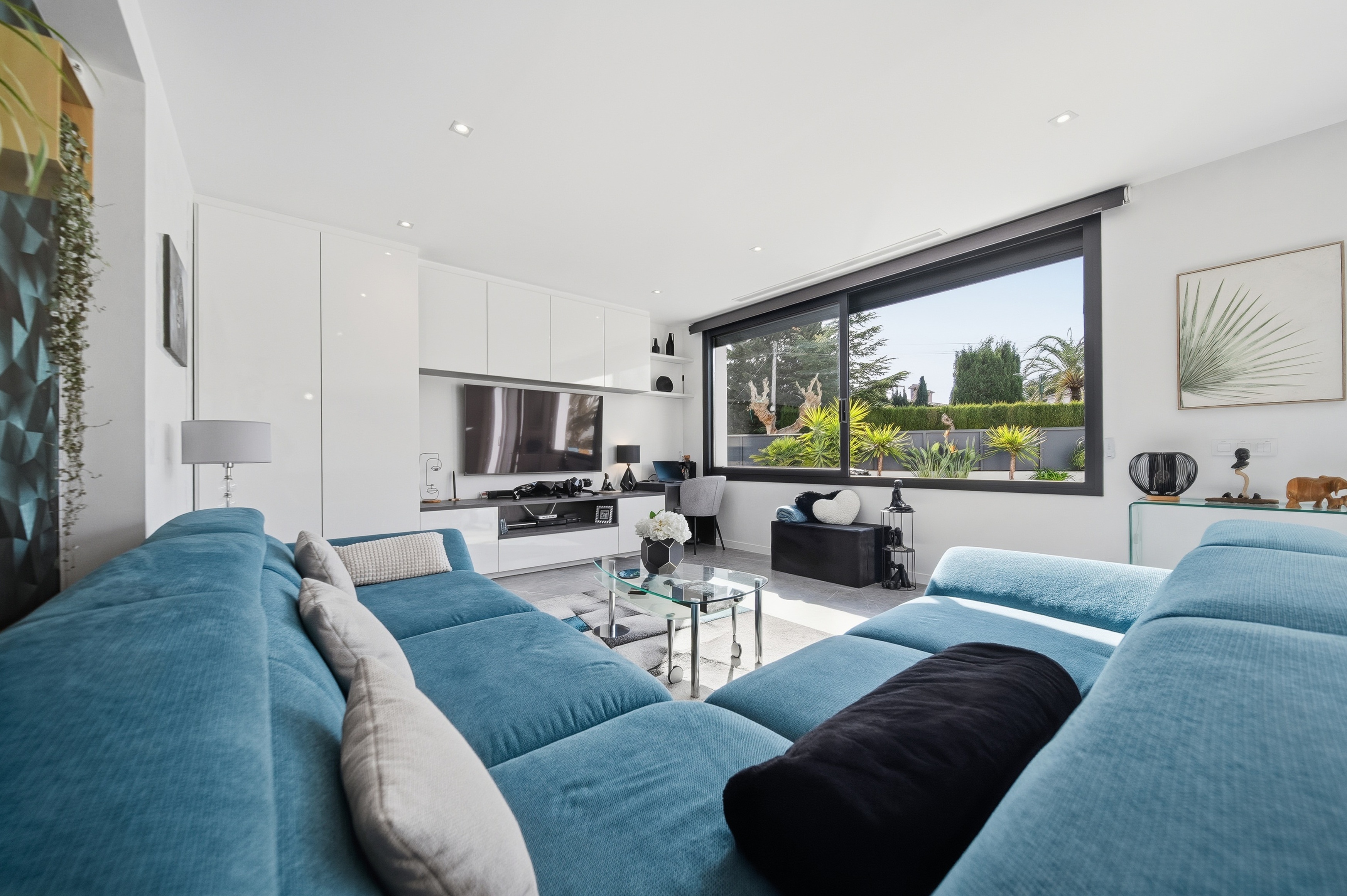 Salón con sofás azules y gran ventanal jardín fotografía inmobiliaria Costa Brava